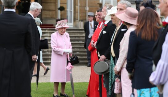 Regina în grădina Palatului Buckingham înconjurată de înalți oficiali