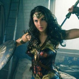 Gal Gadot costumată în Wonder Woman ține în mână o sabie și un disc de protecție
