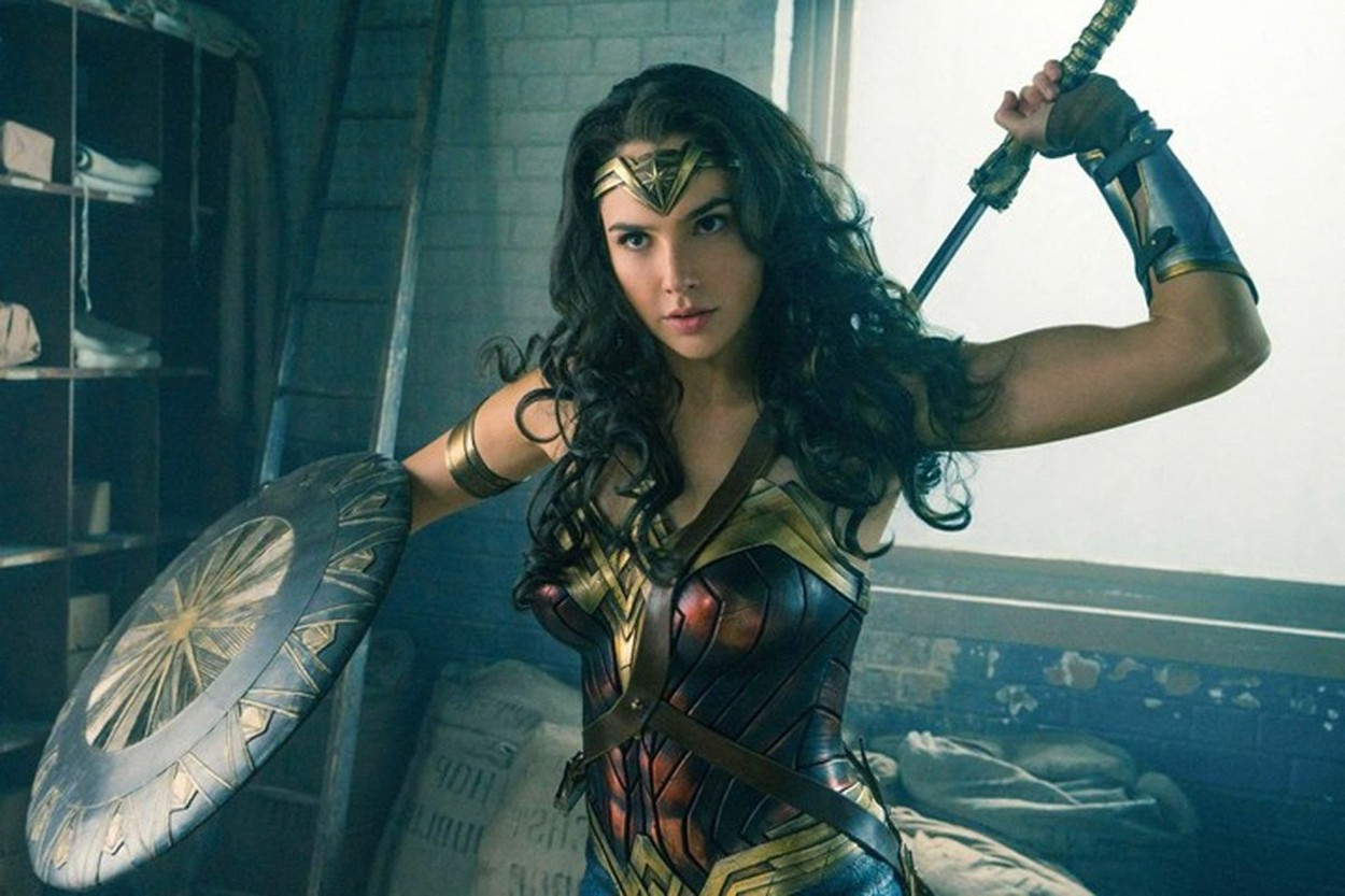 Gal Gadot costumată în Wonder Woman ține în mână o sabie și un disc de protecție