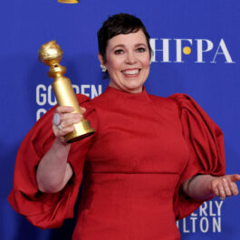 Olivia Colman îmbrăcată cu o rochie roșie pe covorul roșu ține în mână un Glob de Aur