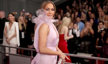 Jennifer Lopez pe covorul roșu îmbrăcată cu o rochie roz pal cu decolteu adânc și fără mâneci