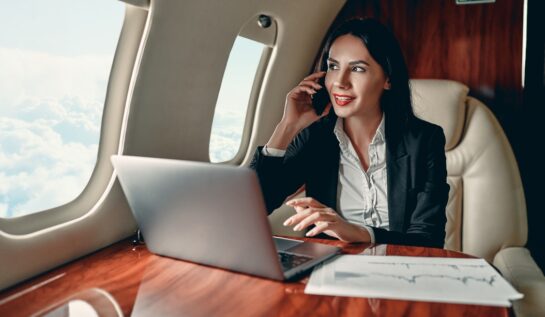 O femeie lucrează pe laptop și vorbește la telefon într-un avion privat
