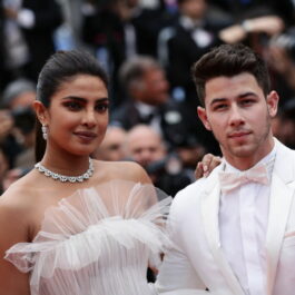Nick Jonas îmbrăcat cu un costum elegant alb alături de Priyanka Chopra îmbrăcată cu o rochie albă pe covorul roșu