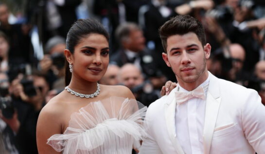 Nick Jonas îmbrăcat cu un costum elegant alb alături de Priyanka Chopra îmbrăcată cu o rochie albă pe covorul roșu