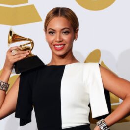Beyonce îmbrăcată cu o rochie jumătate albă și jumătate neagră pe covorul roșu, ține un trofeu, după ce a fist nominalizată la Premiile Grammy