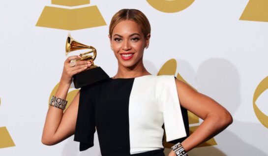 Beyonce îmbrăcată cu o rochie jumătate albă și jumătate neagră pe covorul roșu, ține un trofeu, după ce a fist nominalizată la Premiile Grammy