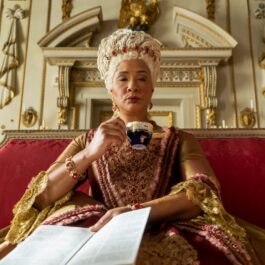 Regina Charlotte bea o ceașcă de ceai în timp ce stă pe tron în Bridgerton