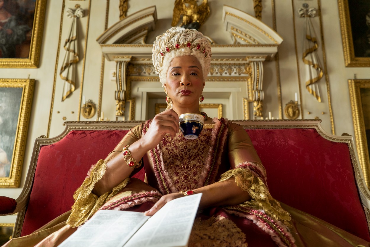 Regina Charlotte bea o ceașcă de ceai în timp ce stă pe tron în Bridgerton