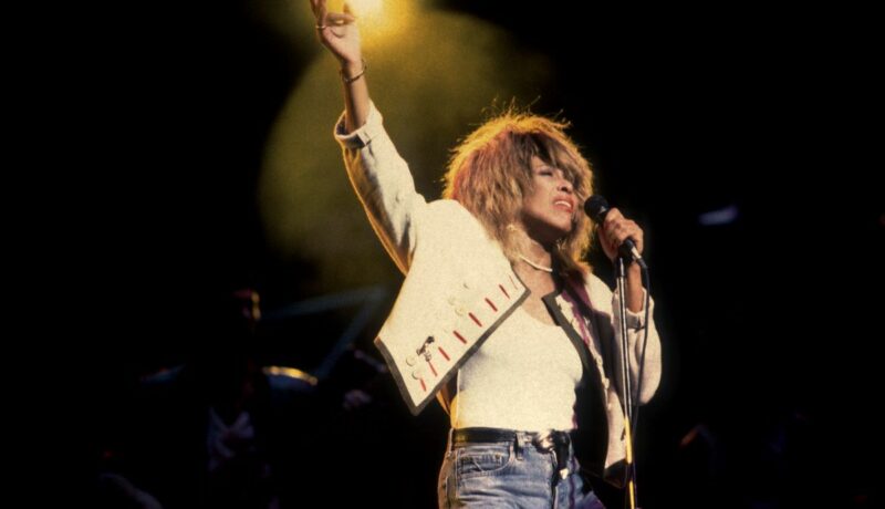 Tina Turner, îmbrăcată cu o geacă și top albe, în timpul unui concert susținut în Chicago, în anul 2000