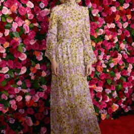Carey Muligan, pe covorul roșu, participând la premiile Tony din 2018, îmbrăcată într-o rochie florală, pozând în fața unui panou de trandafiri.