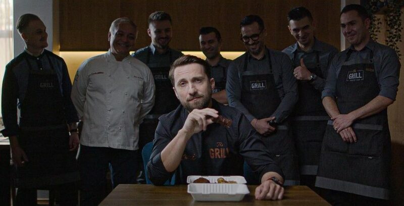 Dani Oțil, la masă, cu mai mulți bucătari în spatele lui
