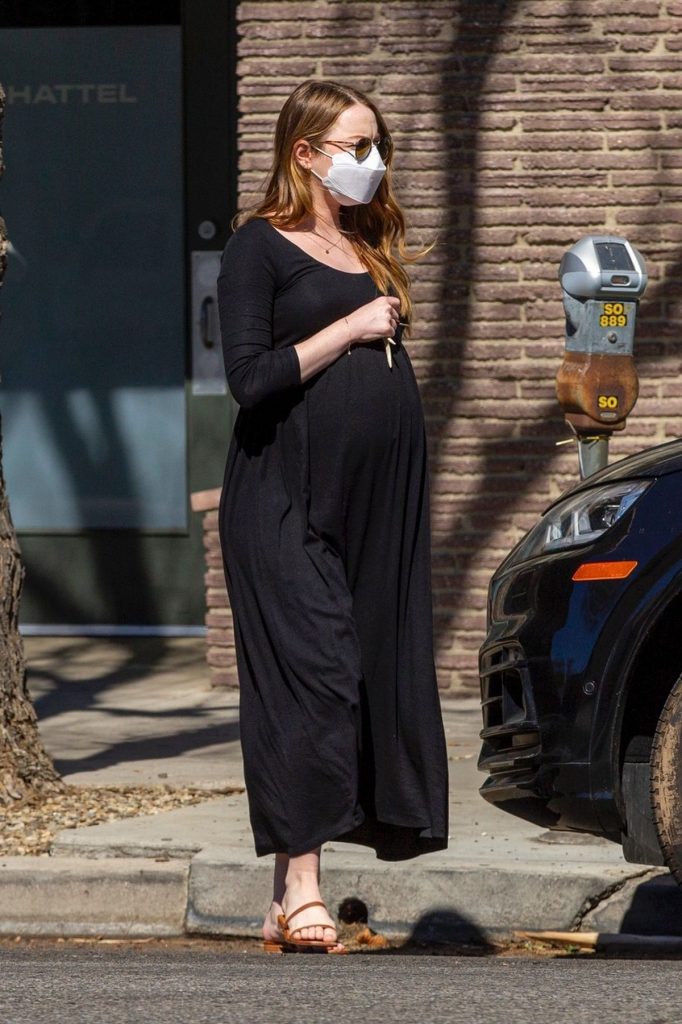 Emma Stone, purtând o rochie lungă, neagră, prin care i se vede burtica de gravidă