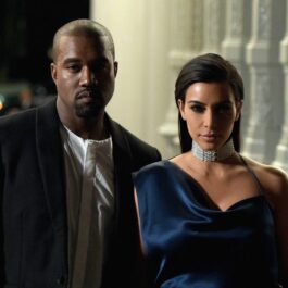 Kim Kardashian îmbrăcată într-o rochie albastră și un colier de diamante la gât, alături de Kanye West, ce poartă o bluză albă și un sacou negru