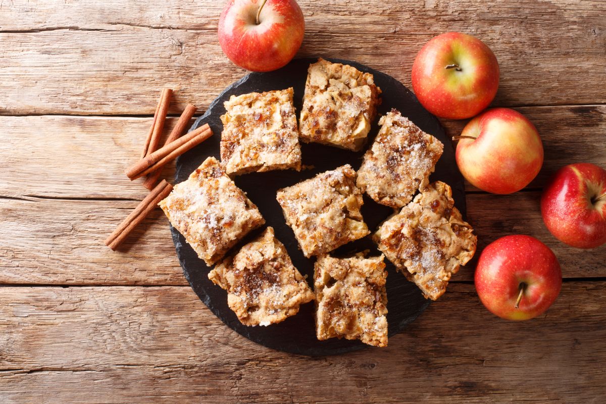 Felii de prăjitură cu mere și scorțișoară, pe un tocător de lemn