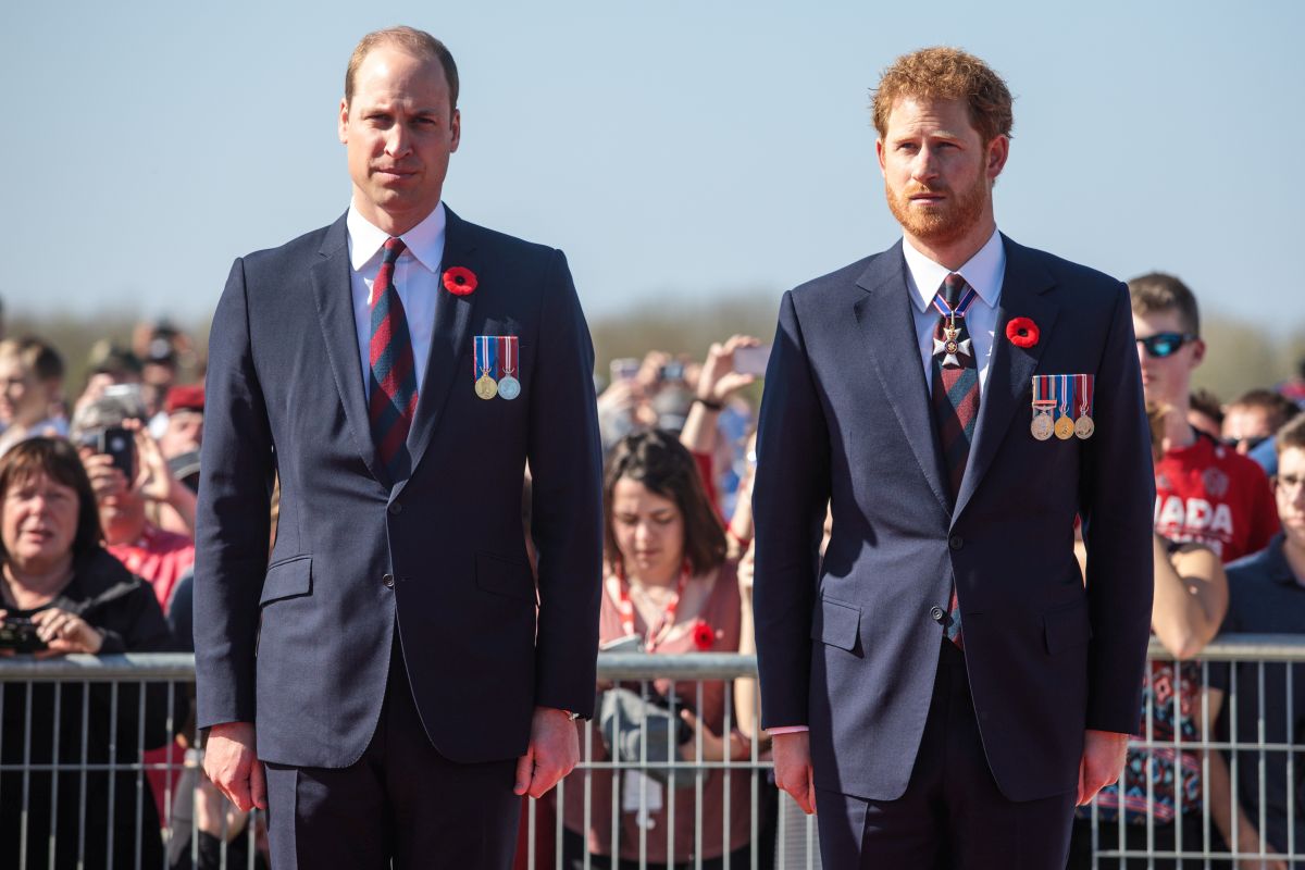 Prințul William, alături de fratele său, îmbrăcați în costume de culoare albastru închis și medalii pe piept