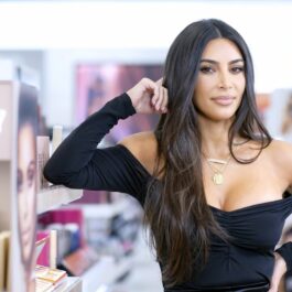 Kim Kardashian, cu o ținută de miliardară, purtând un top de culoare neagră, langă un raft de cosmetice