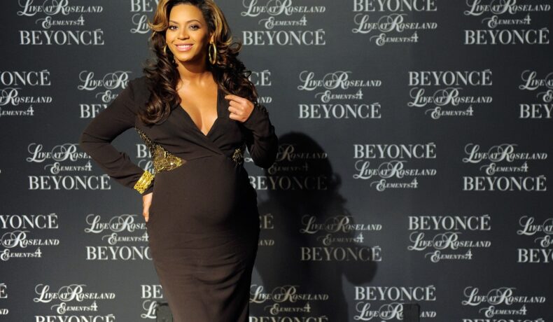 Beyoncé, însărcinată este îmbrăcată într-o rochie neagră, decoltată, cu detalii aurii