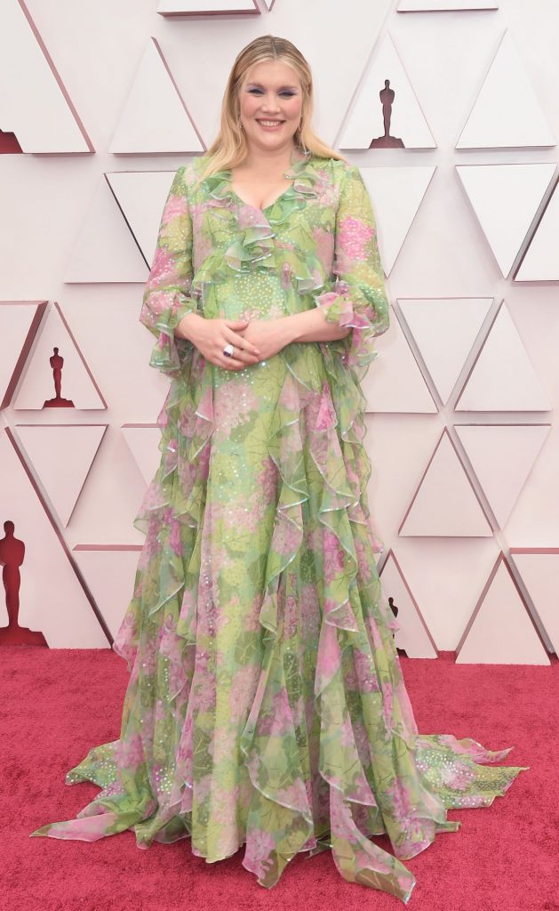 Emerald Fennel poartă o rochie verde, cu flori de culoare roz, pe covorul roșu, la Premiile Oscar 2021