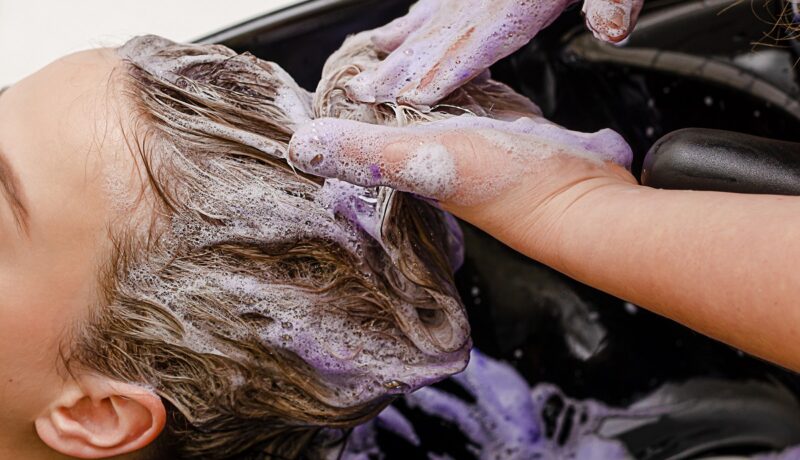 femeie care se spală pe păr cu șampon mov pentru a demonstra efectele acestuia