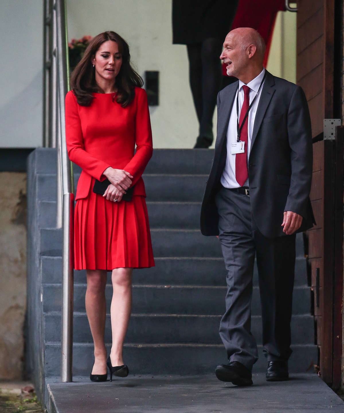 Printre alegerile vestimentare ale lui Kate Middleton este un costum roșu în timp ce coboară scările alături de un bărbat
