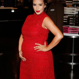 Kim Kardashiane îmbrăcată într-o rochie roșie mulată, fără mâneci. Buzele sunt roșii.