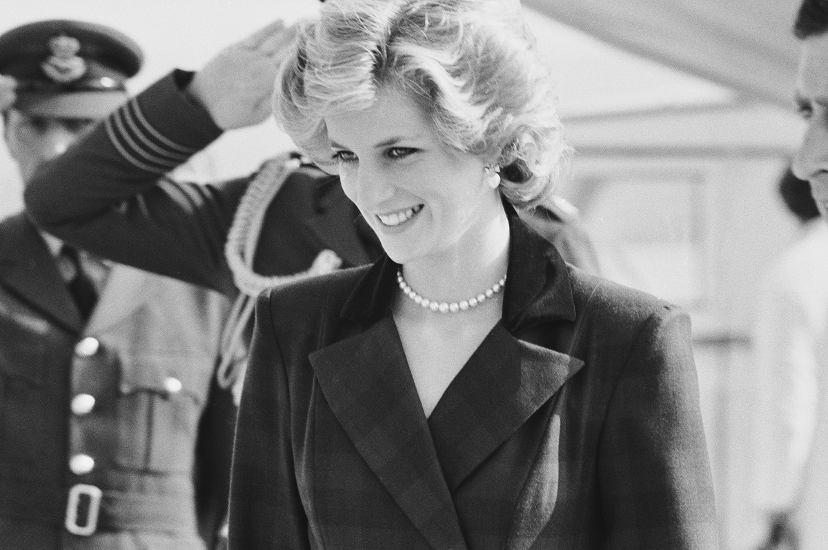 portret al Prințesei Diana care zâmbește la o Întâlnire oficială în timp ce poartă un costum elegant și un colier din perle