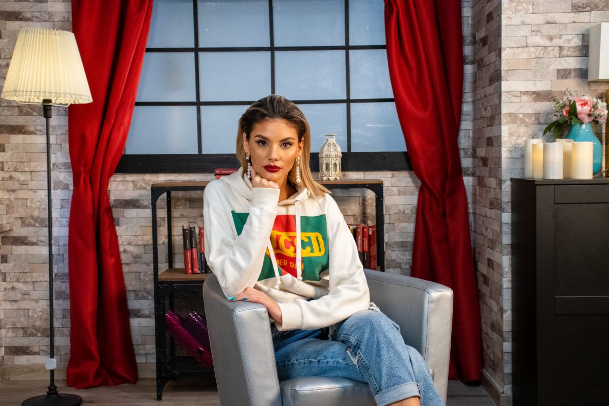 Ramona Olaru, îmbrăcată cu un hanorac Gucci și o pereche de blugi deschiși la culoare, stă pe un scaun în studioul CaTine.ro și își ține mâna sub bărbie.