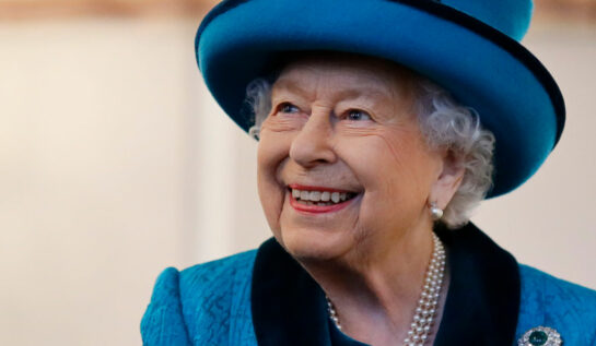 Regina Elisabeta, într-un costum albastru, zâmbitoare, într-o vizită regală