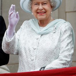 regina Elisabeta curtând pălărie albă și costum alb în timp ce face cu mâna oamenilor, iar în piept poartă diamantele Cullian