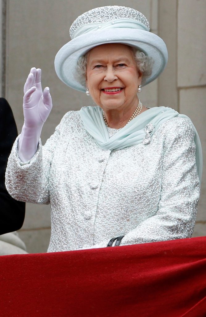 regina Elisabeta curtând pălărie albă și costum alb în timp ce face cu mâna oamenilor, iar în piept poartă diamantele Cullian