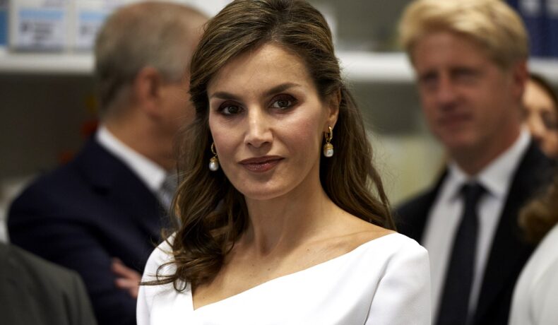Portretul Reginei Letizia a Spaniei într-o vizită oficială, purtând o bluză elegantă albă și o pereche de cercei tip perluțe