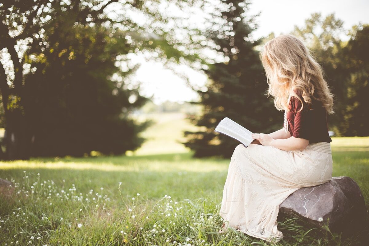 O femeie care stă în iarbă și citește