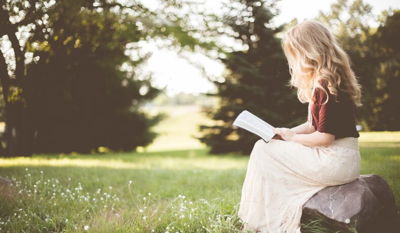O femeie care stă în iarbă și citește