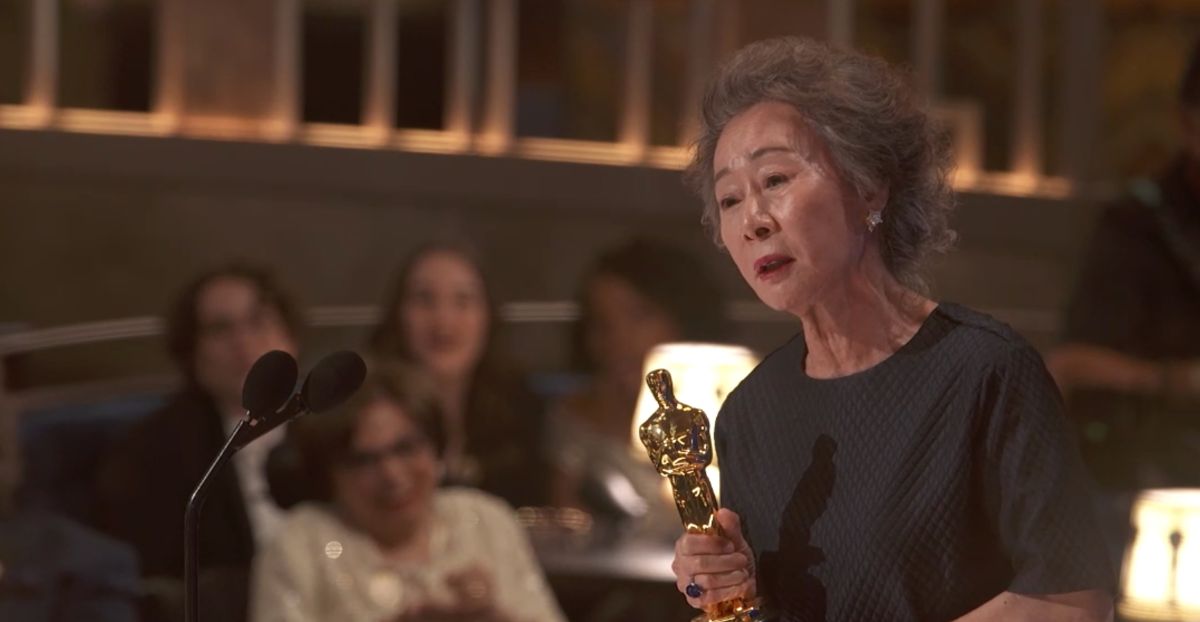 Yuh Jung Youn, îmbăcată într-o rochie închisă la culoare, ține în mână o statuetă Oscar la gala organizată în anul 2021.