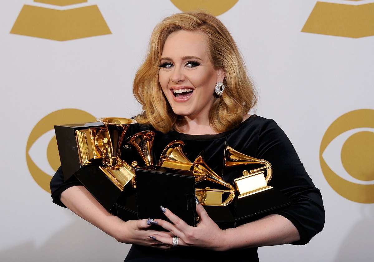 Adele la Premiile Grammy din 2012 zâmbind la public în timp ce ține în brațe cele șase statuete pe care le-a câștigat