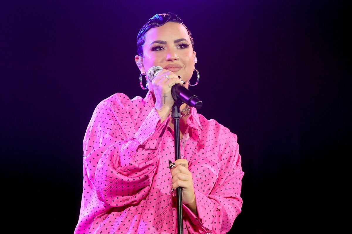 Demi Lovato pe scenă în fața microfonului îmbrăcată într-o rochie roz la premiera evenimentului documentarului său Dancing with the devil în martie 2021