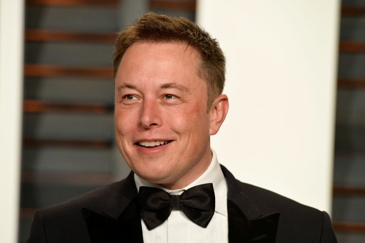 Elon Musk, purtând un costum negru, cămașă albă și papion,