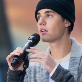 Justin Bieber pe scenă în New York 2015 cântând la NBC's Today în timp ce ține în mână microfonul și poartă o căciulă neagră înainte de a renunța la dreaduri