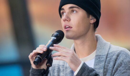 Justin Bieber pe scenă în New York 2015 cântând la NBC's Today în timp ce ține în mână microfonul și poartă o căciulă neagră înainte de a renunța la dreaduri