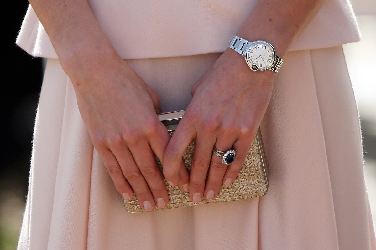 mâinile Ducesei Kate în timp ce ține o geantă în mână și este îmbrăcată cu o fustă roz pal