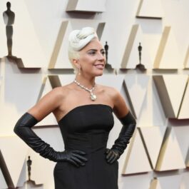 Lady Gaga poartă o rochie neagră de satin, fără umeri, și mănuți lungi. Aceasta participă la cea de-a 91- ediție a Premiilro Oscar