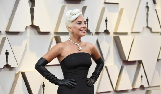 Lady Gaga poartă o rochie neagră de satin, fără umeri, și mănuți lungi. Aceasta participă la cea de-a 91- ediție a Premiilro Oscar