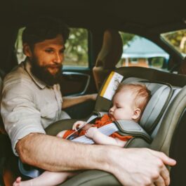 Un tată își aranjează bebeușul în scaunul rear-facing