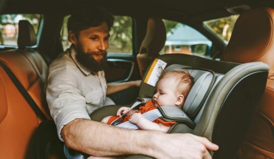 Un tată își aranjează bebeușul în scaunul rear-facing