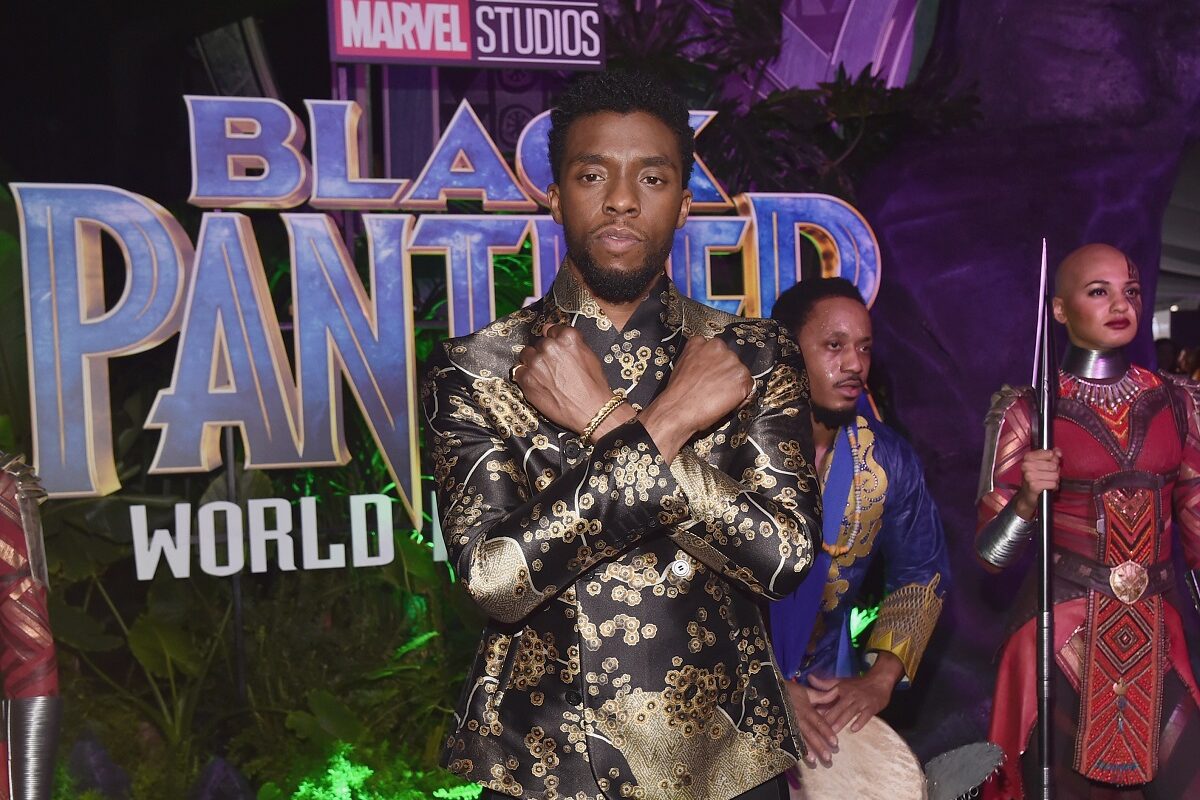actorul Chadwick Boseman îmbrăcat într-un costum argintiu ținând mâinile încrucișate la premiera filmului Pantera Neagră