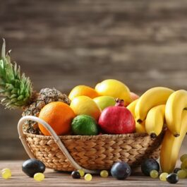 Un coș cu mai multe fructe: ananas, banane, avocado, citrice.