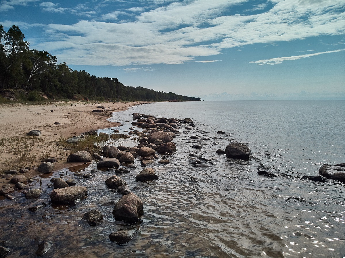 plajă acoperită cu stânci și apă cu un cer albastru și senin într-o imagine care denotă vacanța de vis