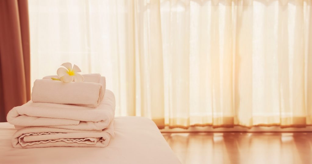 cameră de hotel cu draperii ți proasoape albe așezate pe un pat care să explice de ce sunt folosite așternuturile albe în camera de hotel