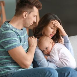 Un bărbat și o femeie care suferă de depresie postnatală își țin în brațe bebelușul