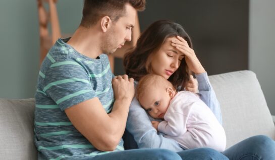 Un bărbat și o femeie care suferă de depresie postnatală își țin în brațe bebelușul